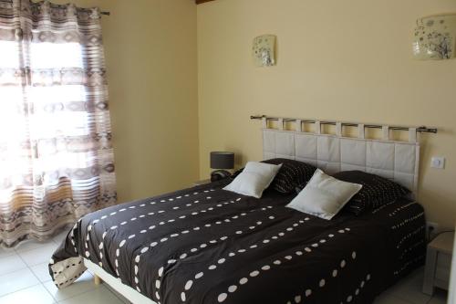 Un dormitorio con una cama con sábanas blancas y negras y una ventana en Le Pailler de la Planque, en Camplong