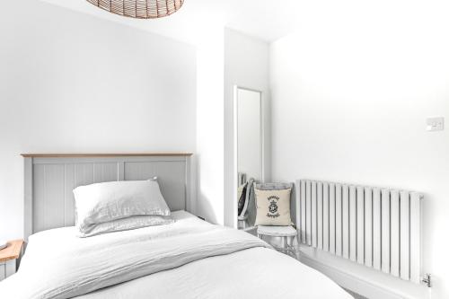 a white bedroom with a bed and a chair at The Gate Cornwall in Looe