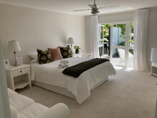 Biała sypialnia z łóżkiem i balkonem w obiekcie Hahei Bed and Breakfast w mieście Hahei
