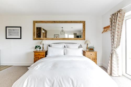 a bedroom with a white bed and a mirror at The Gate Cornwall in Looe