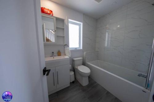 a white bathroom with a tub and a toilet and a sink at Chalet le Caribou- Chalets Galaxia in Saint-Alphonse-Rodriguez