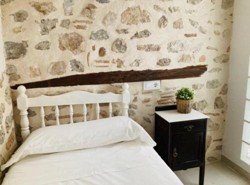 a bedroom with a white bed and a stone wall at Chic & Sailor Beach Home in Peñíscola