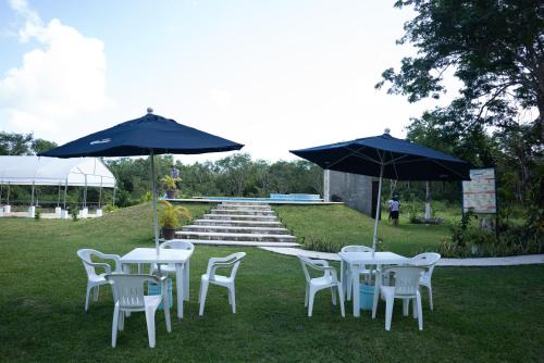 a group of tables and chairs with umbrellas in the grass at Aldea Isla Sagrada in Cozumel