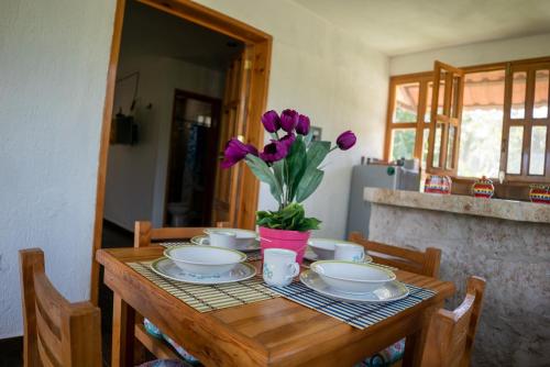 a wooden table with a vase of purple flowers on it at Aldea Isla Sagrada in Cozumel