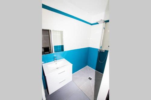 La salle de bains est pourvue de murs bleus et d'un lavabo blanc. dans l'établissement La Maison réseau Cycle et Gites, à Clécy