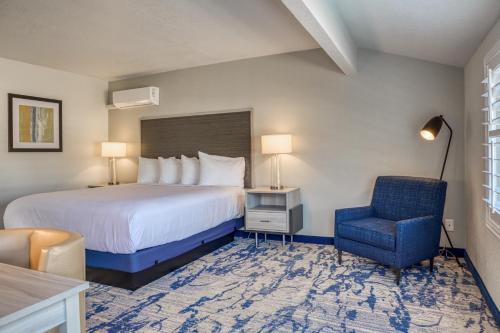 a hotel room with a bed and a blue chair at Creekside Inn Downtown in Cambria