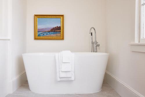 a bathroom with a white tub and a sink at Kennebunkport Captains Collection in Kennebunkport