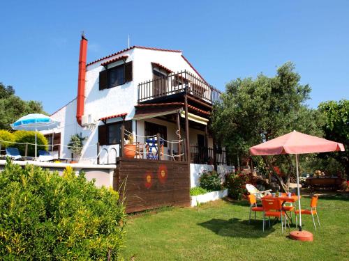 een huis met een tafel en stoelen en een paraplu bij Villa Papoura Homeleader in Delimanolianá