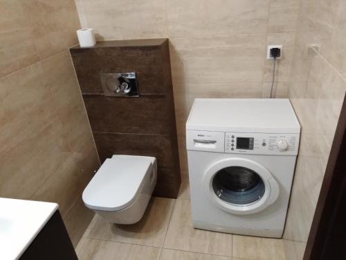 a bathroom with a toilet and a washing machine at Apartament MAZURIA2 in Ełk