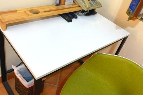 a white desk with a green chair and a phone at Alebrije Hotel Boutique in Guadalajara
