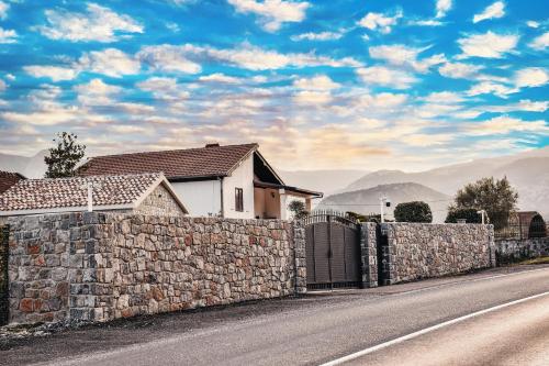 a house with a stone fence next to a road at Apartments Monte Green in Virpazar