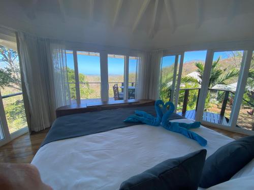 a bedroom with a large bed with a blue ribbon on it at Mikado Natural Lodge in Playa Avellana