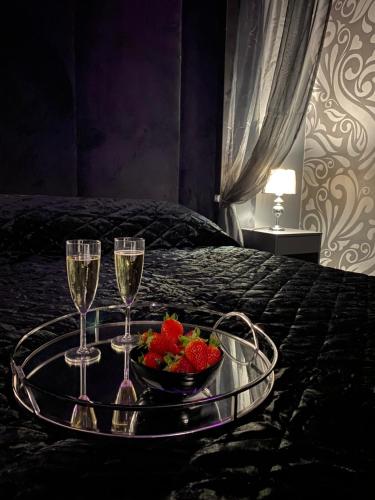 a tray with two glasses of wine and strawberries on a bed at Gray Apartment in Wrocław