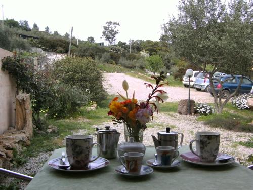 une table avec des assiettes et des tasses et un vase de fleurs dans l'établissement B&B Valli Verdi, à Alghero