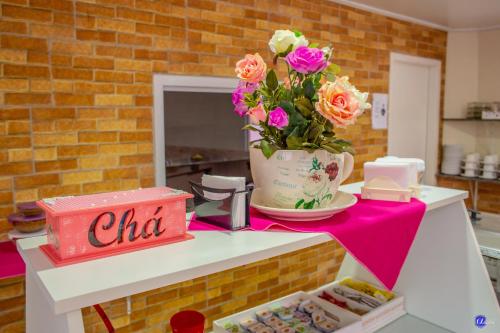 een tafel met een vaas met bloemen erop bij Pousada do Recanto Feliz in Torres