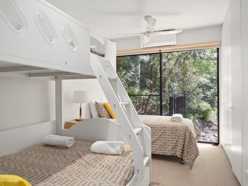 a bedroom with a bunk bed and a bed with a bunk bed at Charming Beach Home with Plenty of Outdoor Spaces in Avoca Beach
