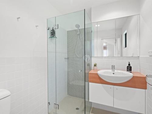 a white bathroom with a sink and a shower at Charming Beach Home with Plenty of Outdoor Spaces in Avoca Beach