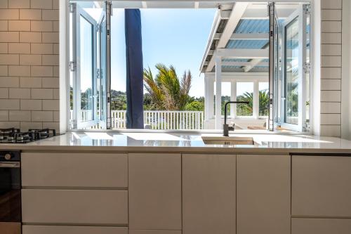 a kitchen with a sink and a large window at Bluebelle - Stay Waiheke in Oneroa