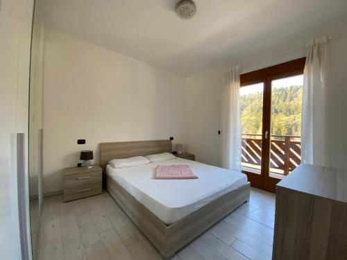 ein weißes Schlafzimmer mit einem Bett und einem Balkon in der Unterkunft Residenza al Parco Termale - Comano Terme in Comano Terme