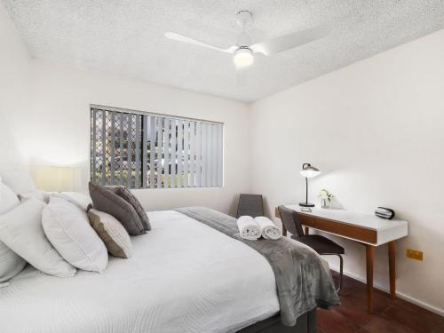 a white bedroom with a bed and a desk at Beachfront Terrigal - 4/24 Terrigal Espl in Terrigal