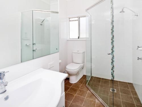 a bathroom with a toilet and a glass shower at Comfy Beachfront Unit, Unbeatable Location & Views in Avoca Beach