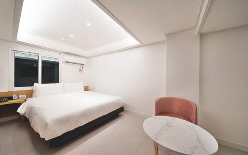 a white bedroom with a bed and a chair at Busan Seomyeon Business Hotel J7 in Busan
