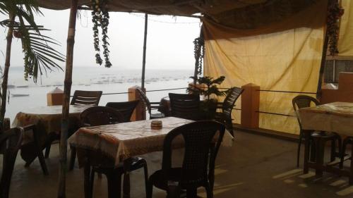 バラナシにあるSunrise Lodgeのテーブルと椅子が備わり、海の景色を望むレストラン