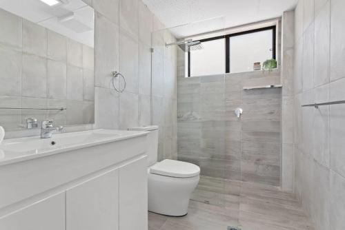 a white bathroom with a toilet and a sink at Bay Village - Shoal Bay Apartments in Shoal Bay