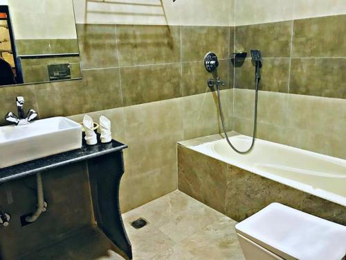 uma casa de banho com um lavatório, uma banheira e um WC. em Hotel the Narayani em Maruwā Ghāt