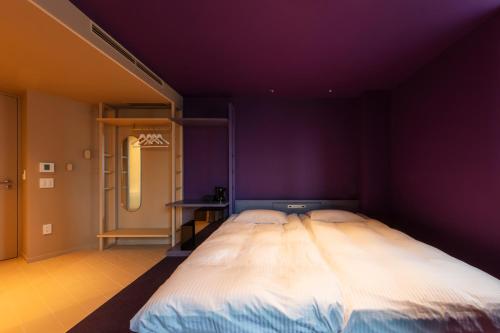 a large bed in a room with purple walls at toggle hotel suidobashi TOKYO in Tokyo