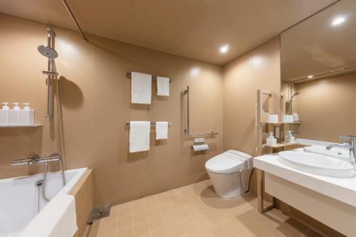 a bathroom with a toilet and a tub and a sink at toggle hotel suidobashi TOKYO in Tokyo