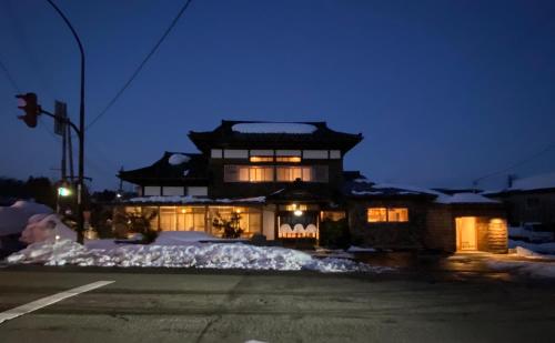 a house with an asian building in the snow at night at やどバーTATSUJi in Joetsu