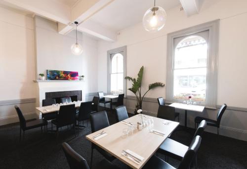 a dining room with tables and chairs and a fireplace at Ramsgate Hotel by Nightcap Social in Adelaide