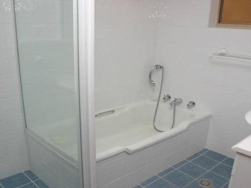 a bath tub with a shower in a bathroom at Charming Beach Getaway, Close to Cafe & Restaurant in Terrigal