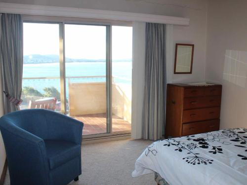 a bedroom with a bed and a chair and a balcony at Charming Beach Getaway, Close to Cafe & Restaurant in Terrigal