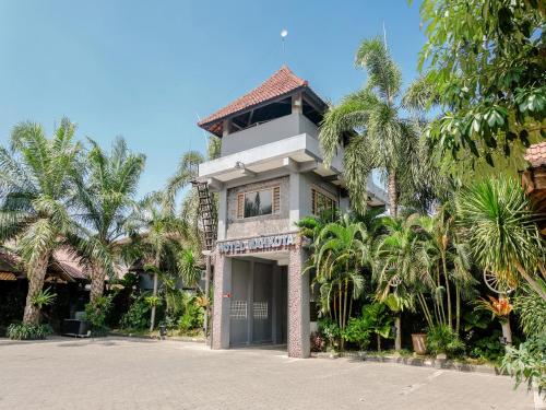 a building with palm trees in front of it at Hotel Mahkota Plengkung by ecommerceloka in Banyuwangi