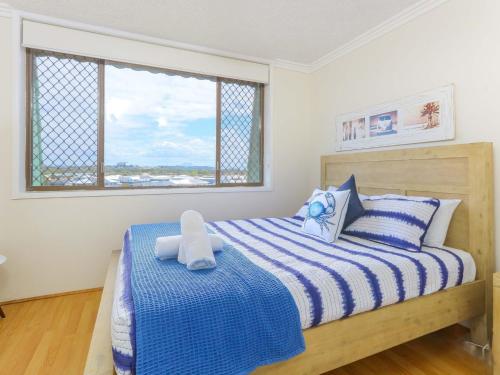 a bedroom with a blue and white striped bed with a window at Kingsway Apartment 12 in Kingscliff