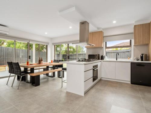 a kitchen with white cabinets and a table with a dining room at La Bella On Allambi in Capel Sound