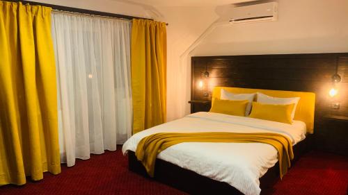 um quarto com uma cama grande e cortinas amarelas em Pensiunea Domnika em Dej