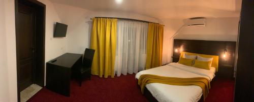 a hotel room with a bed and a yellow curtain at Pensiunea Domnika in Dej