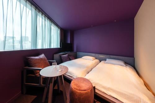 two beds in a room with a table and a window at toggle hotel suidobashi TOKYO in Tokyo