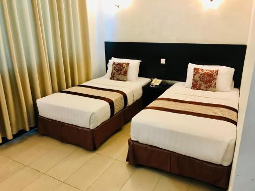 2 camas en una habitación de hotel en My Inn Hotel Lahad Datu, Sabah, en Lahad Datu
