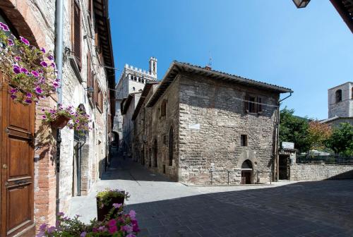 un vicolo in un vecchio edificio in pietra con fiori viola di Residenza Di Via Piccardi a Gubbio