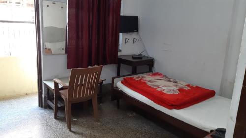 巴特那的住宿－Hotel Yuvraj，一间卧室配有一张床、一把椅子和镜子