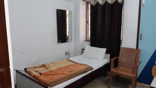 a small bedroom with a bed and a chair at Hotel Yuvraj in Patna