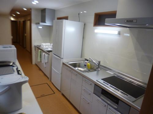 a kitchen with a sink and a refrigerator at ホステルたつみや in Sado