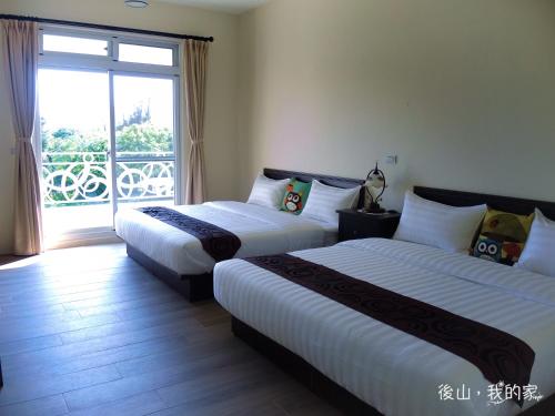 two beds in a hotel room with a balcony at 後山，我的家 in Fenglin