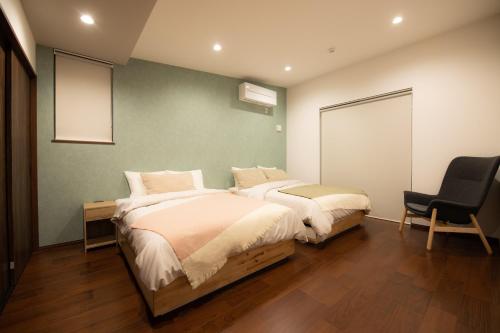 1 dormitorio con 2 camas y 1 silla en Koti Yamanakako next to Hananomiyako Kouen, en Yamanakako