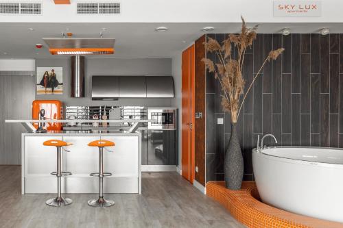 a kitchen with a tub and a kitchen with orange stools at sky ORANGE jacuzzi sauna 28 FLOOR in Klaipėda