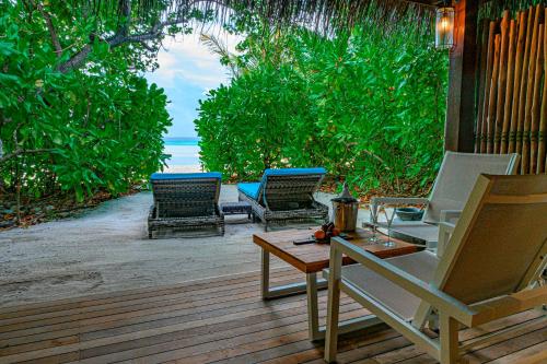 a patio with chairs and a table and a view of the ocean at Constance Moofushi Maldives - All Inclusive in Himandhoo 